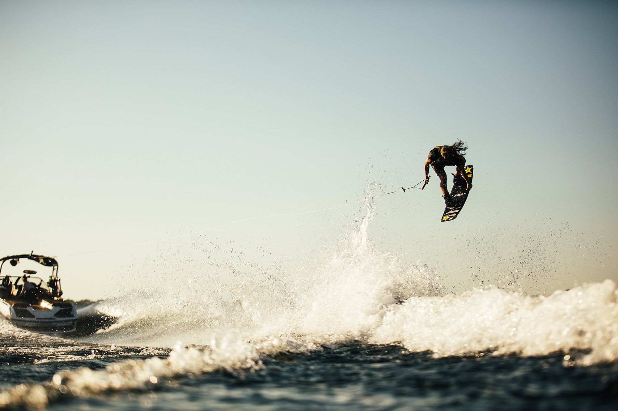 Jobe rider launching a wakeboard trick behind a boat