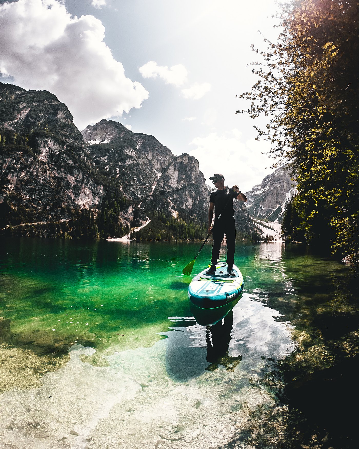 Stand-up paddler on a green alpine lake