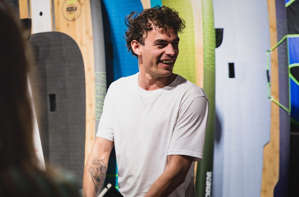 William Doornekamp lachend voor een wand met Jobe-paddleboards